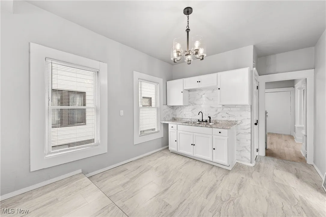 Kitchen featuring a notable chandelier, decorative light fixtures, sink, and white cabinetry