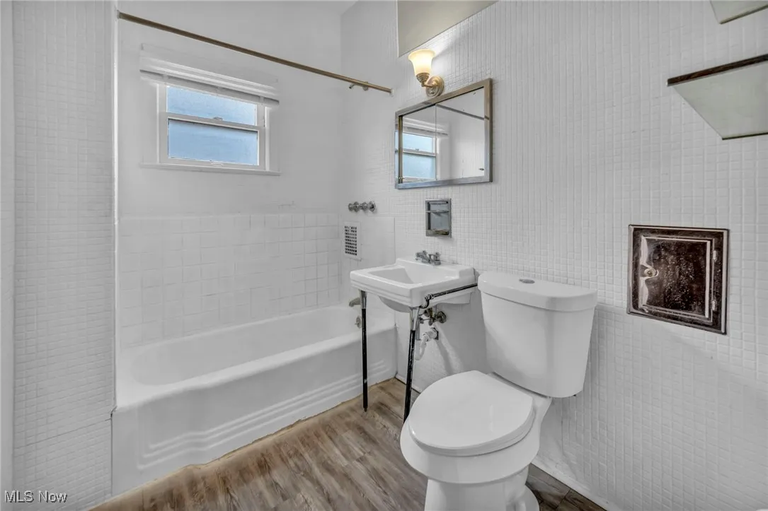 Bathroom with shower / bath combination, wood finished floors, and toilet