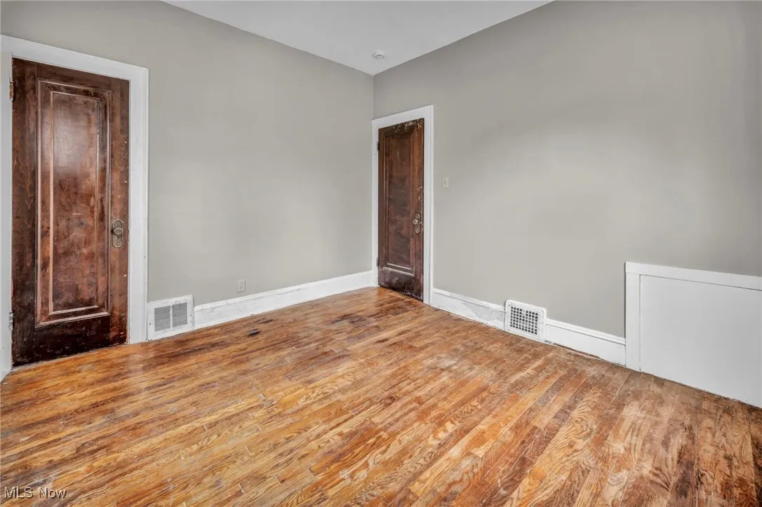 Unfurnished room with baseboards, wood finished floors, and visible vents