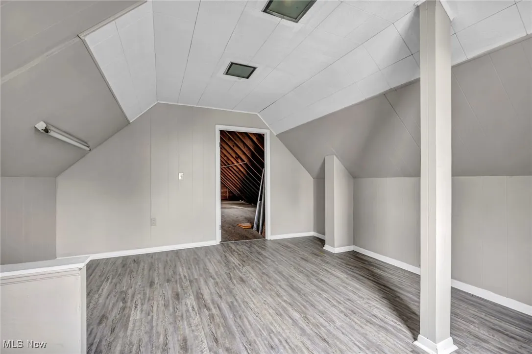 Bonus room featuring lofted ceiling, wood finished floors, and baseboards