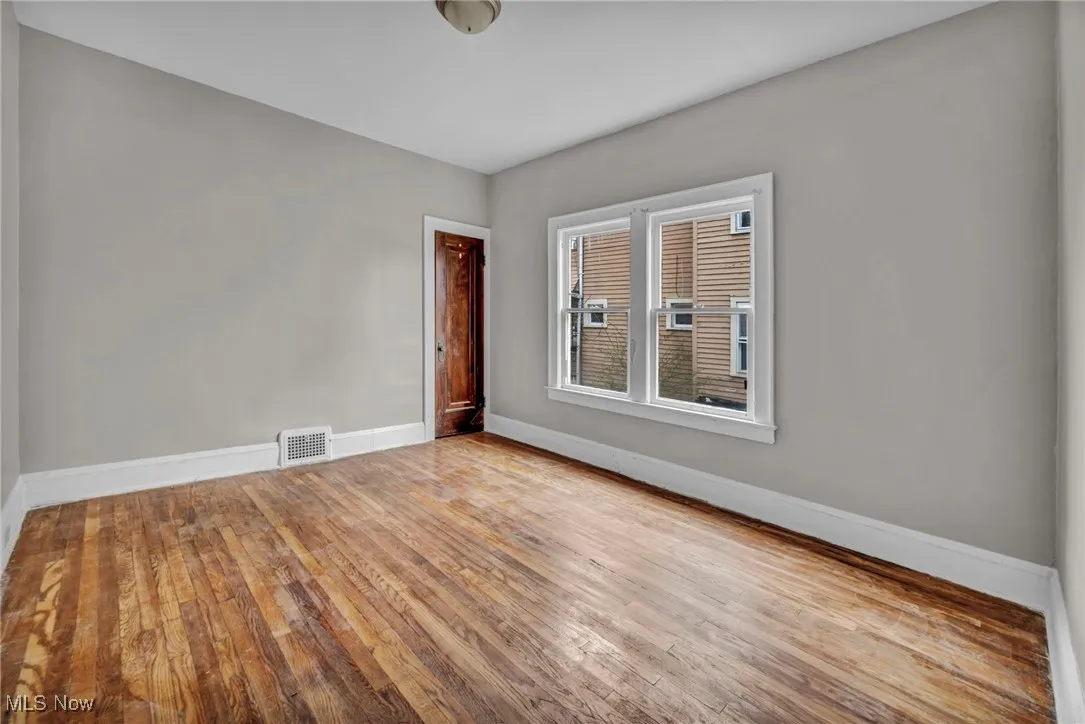 Spare room with hardwood / wood-style flooring, visible vents, and baseboards