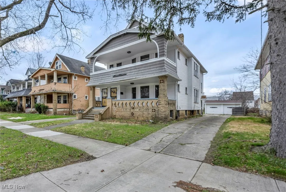 Traditional style home featuring a chimney, a front lawn, a balcony, an outdoor structure, and a porch