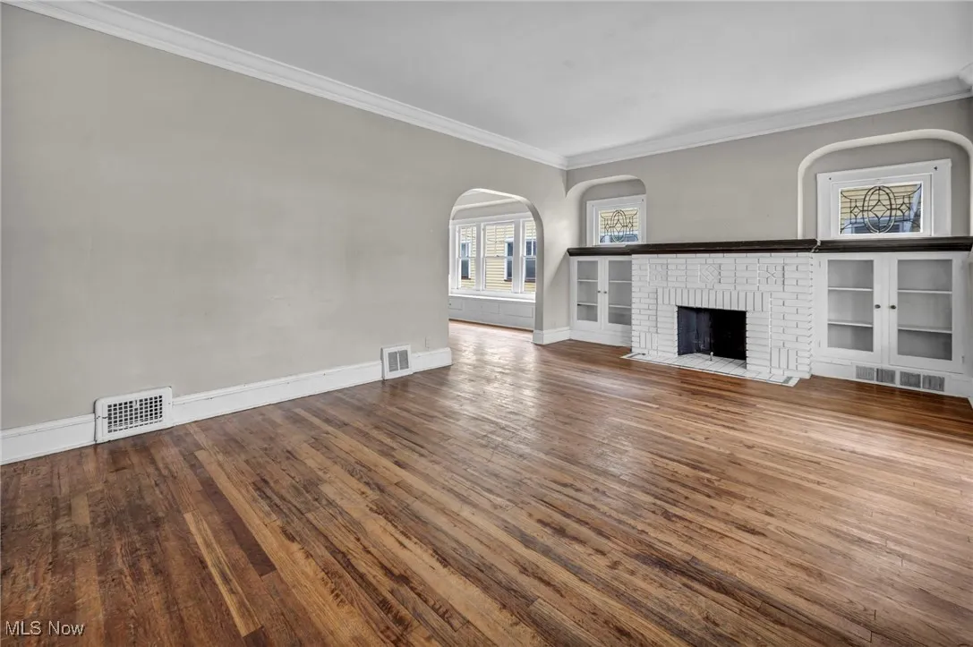 Unfurnished living room with visible vents and ornamental molding