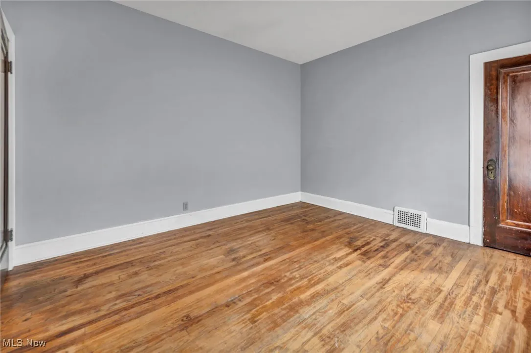 Spare room with baseboards, wood finished floors, and visible vents