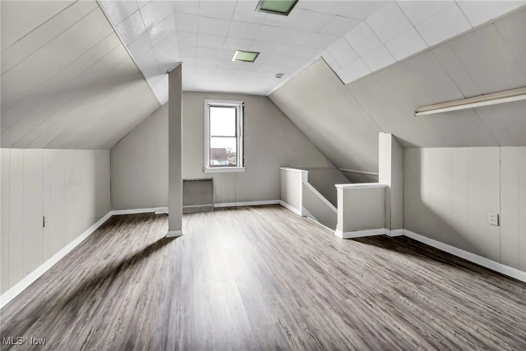 Bonus room featuring baseboards, vaulted ceiling, and wood finished floors