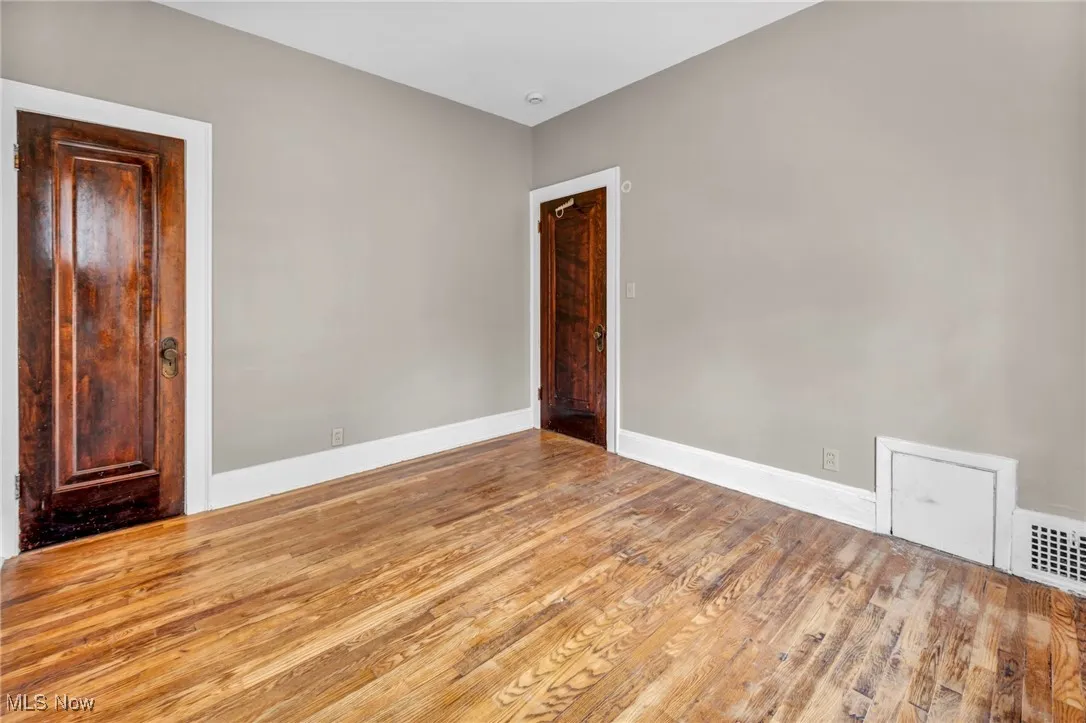 Unfurnished room featuring baseboards, wood finished floors, and visible vents
