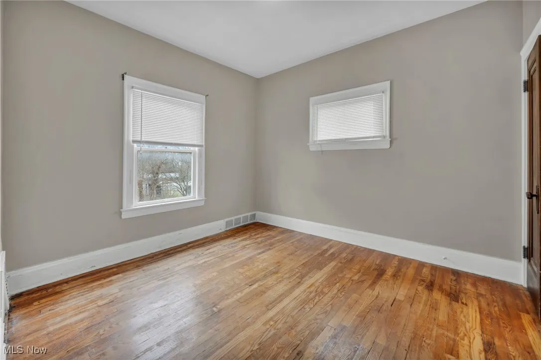 Spare room with wood-type flooring, baseboards, and visible vents