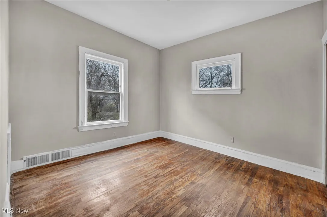 Spare room featuring baseboards, hardwood / wood-style flooring, and visible vents