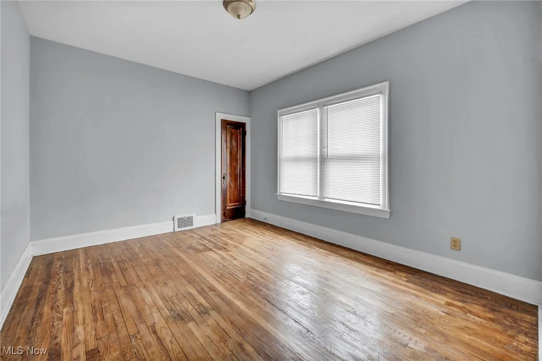 Empty room featuring baseboards, visible vents, and hardwood / wood-style flooring