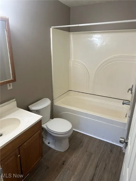 Full bathroom featuring vanity, wood finished floors, a textured ceiling, toilet, and bathtub / shower combination