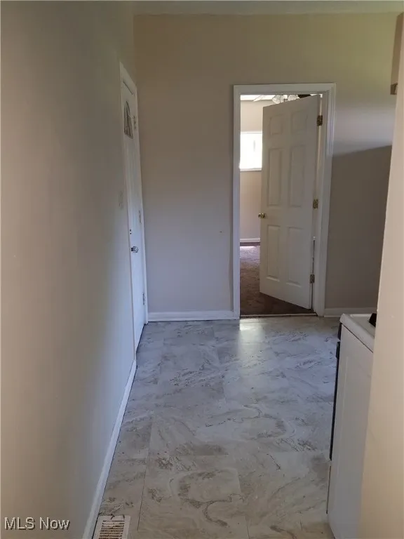 Corridor featuring washer / clothes dryer, visible vents, and baseboards