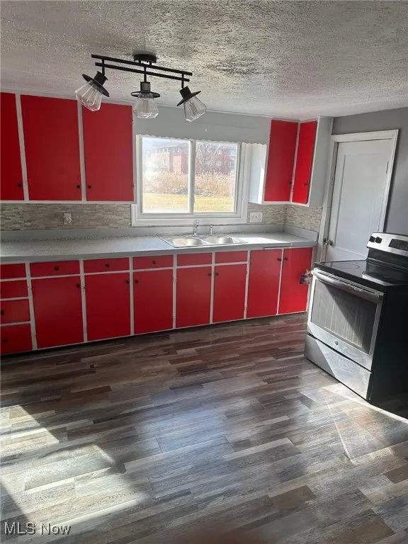 Kitchen featuring a sink, electric range, a textured ceiling, dark wood-style flooring, and red cabinets