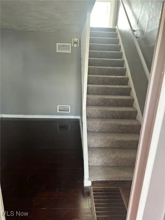 Stairs with visible vents, baseboards, and wood finished floors