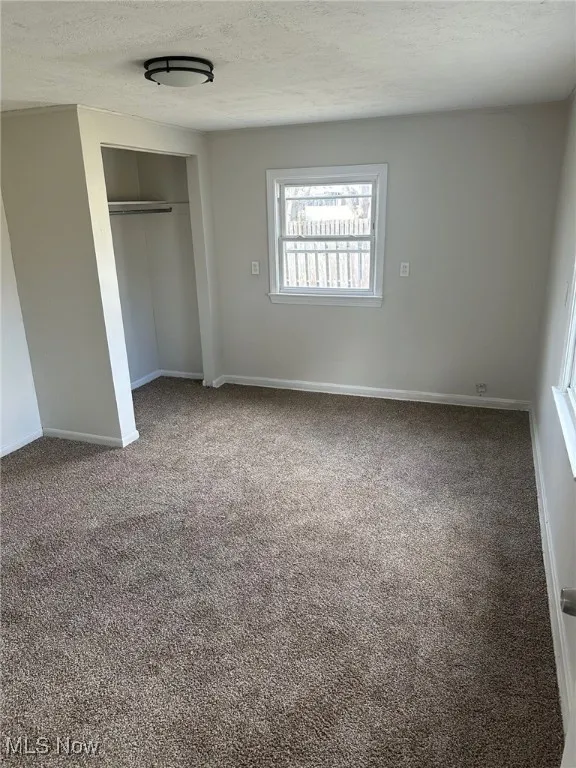 Unfurnished bedroom with baseboards, a closet, carpet flooring, and a textured ceiling