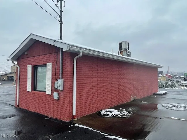 View of side of property with brick siding and cooling unit