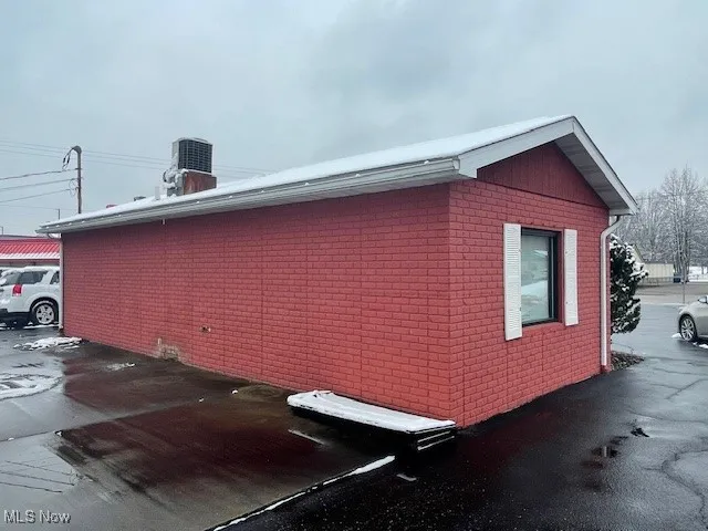 View of side of property featuring cooling unit and brick siding