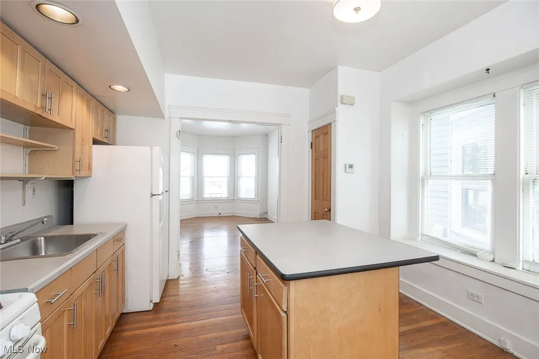 Kitchen with dark wood finished floors, open shelves, a kitchen island, a sink, and white appliances