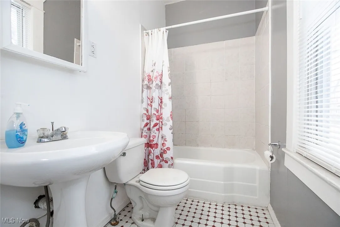 Bathroom with toilet, baseboards, and shower / bath combo with shower curtain