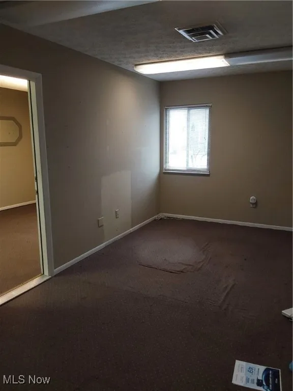 Unfurnished room with carpet floors, visible vents, and baseboards