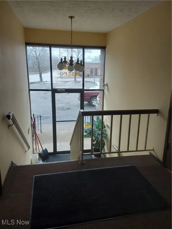 Stairs with a healthy amount of sunlight, a notable chandelier, and a textured ceiling