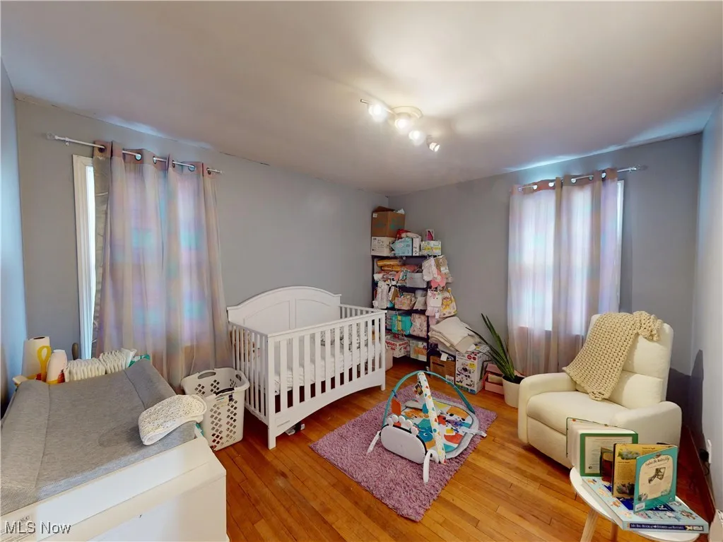 Bedroom with a nursery area and wood finished floors