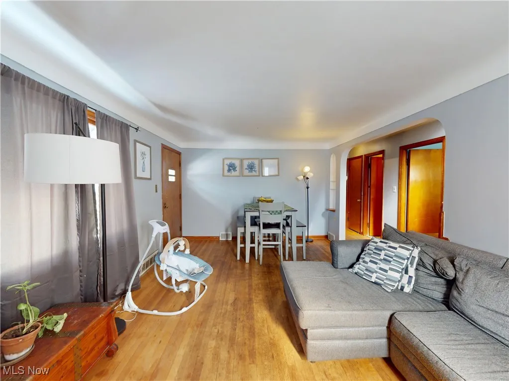 Living area featuring arched walkways, light wood-type flooring, and baseboards