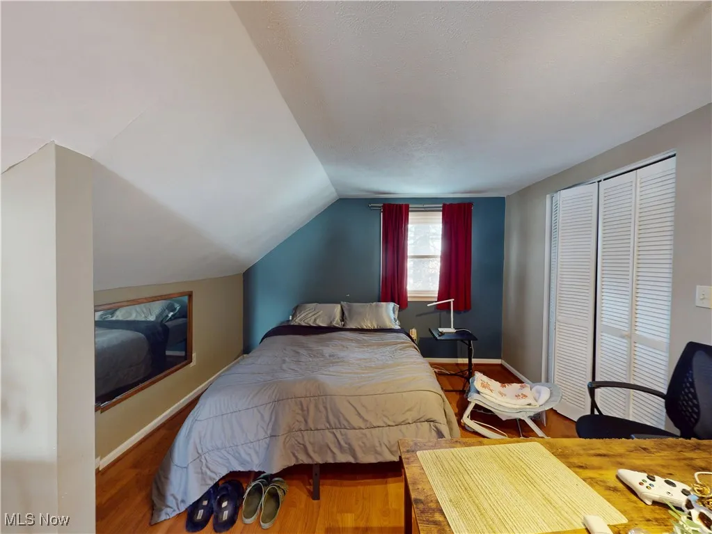 Bedroom featuring lofted ceiling, baseboards, and wood finished floors