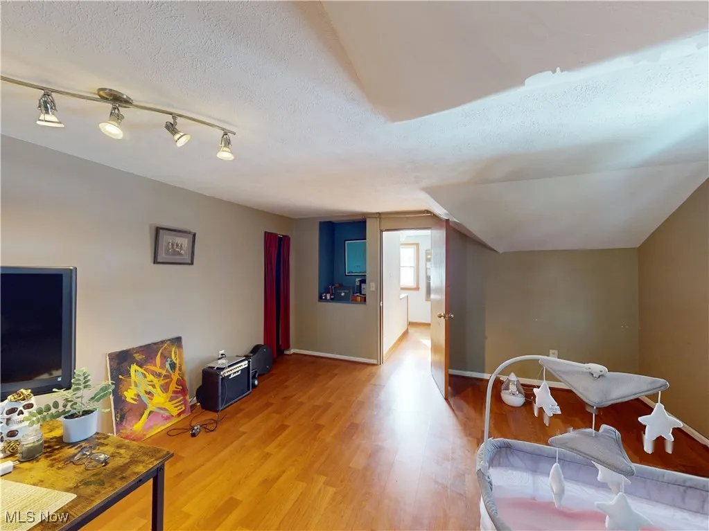Playroom featuring light wood-type flooring, baseboards, and a textured ceiling