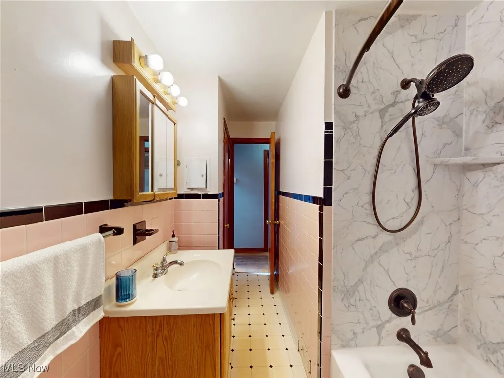 Bathroom featuring vanity, bathing tub / shower combination, and tile walls