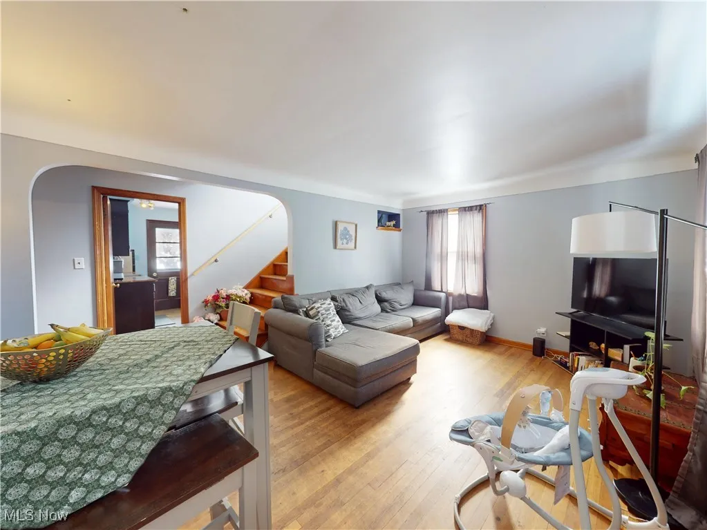 Living area featuring light wood finished floors, baseboards, stairs, and arched walkways