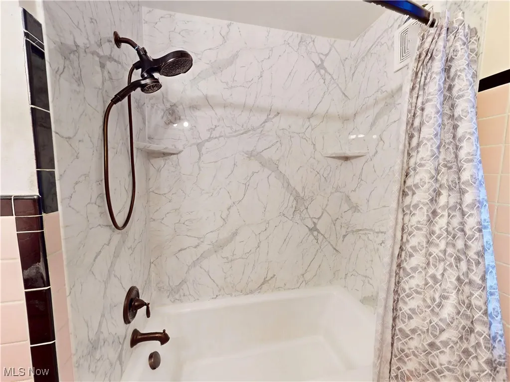 Bathroom with visible vents and shower / bathtub combination with curtain