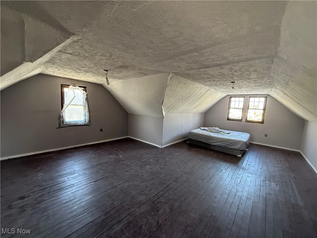 Bonus room with plenty of natural light, a textured ceiling, and dark wood-type flooring