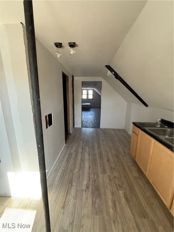 Hallway featuring dark wood finished floors, vaulted ceiling, and a sink