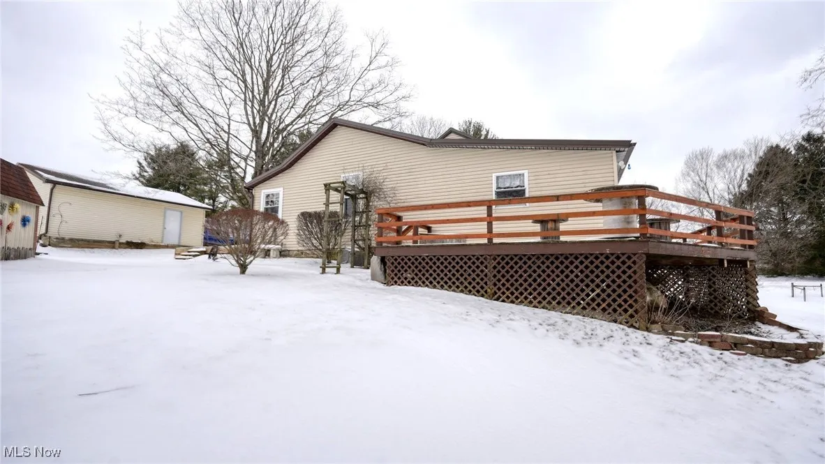Snow covered property featuring a deck and an outdoor structure
