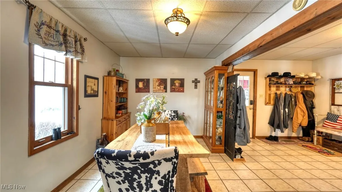 Dining area featuring light tile patterned floors, baseboards, and a drop ceiling