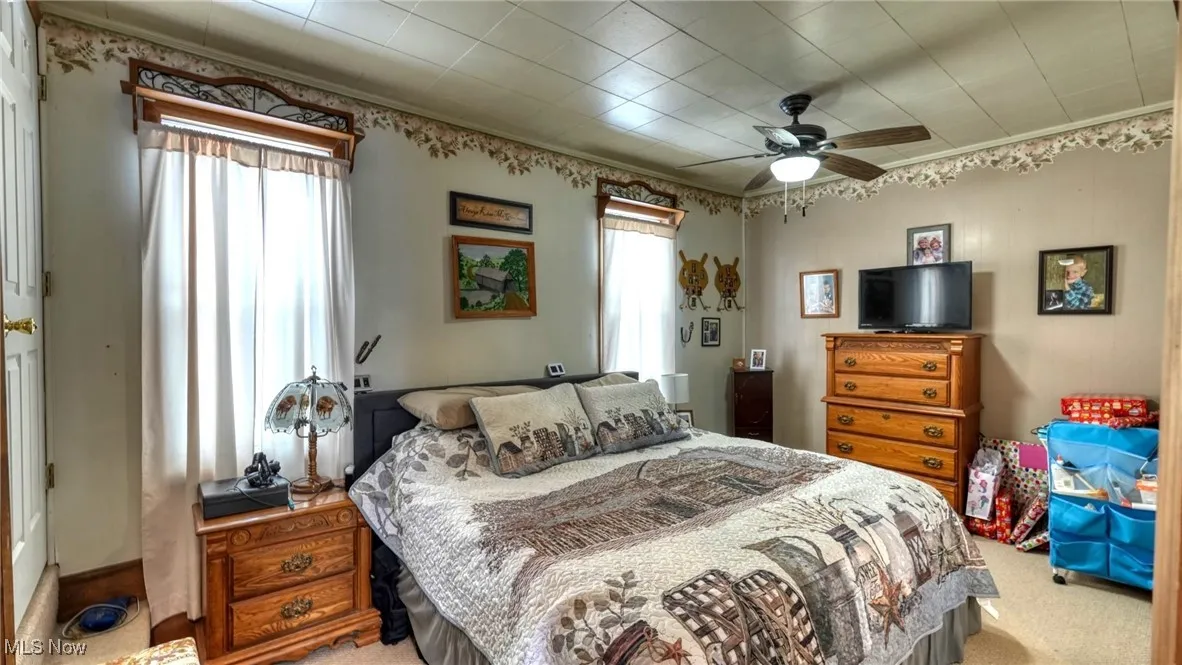 Bedroom featuring light carpet, a ceiling fan, and crown molding