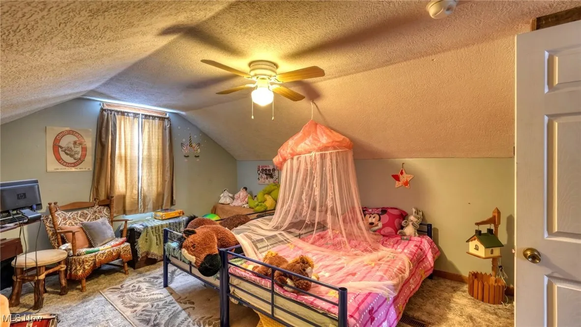 Bedroom featuring vaulted ceiling, a textured ceiling, and ceiling fan