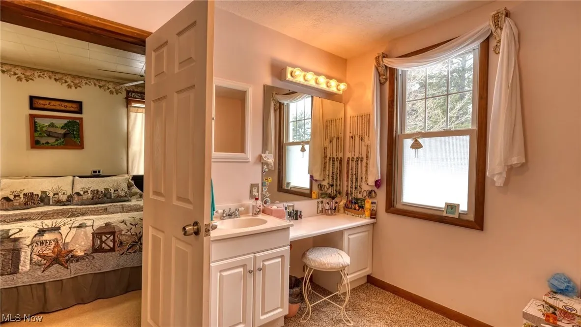 Bathroom with a textured ceiling, vanity, and baseboards