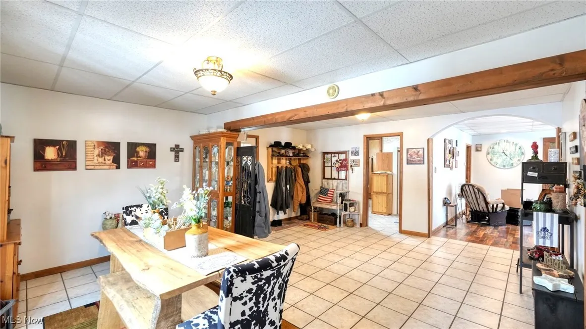 Dining room featuring a drop ceiling, tile patterned flooring, arched walkways, and baseboards