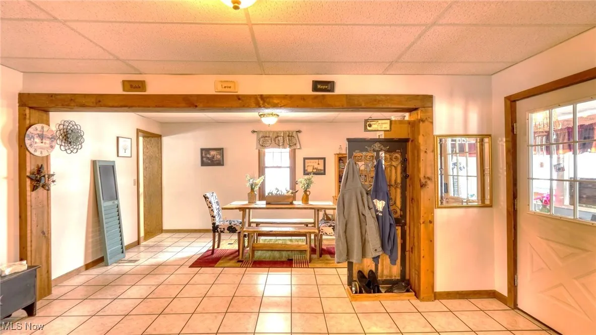 Dining room with light tile patterned floors, a drop ceiling, and baseboards
