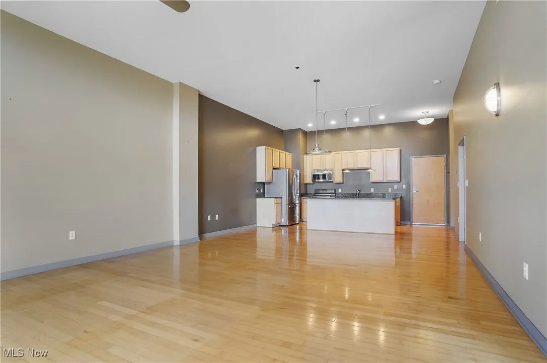 Kitchen with appliances with stainless steel finishes, dark countertops, light wood-style floors, open floor plan, and a center island