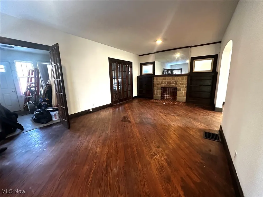 Unfurnished living room featuring dark wood-style flooring, a fireplace, visible vents, and baseboards