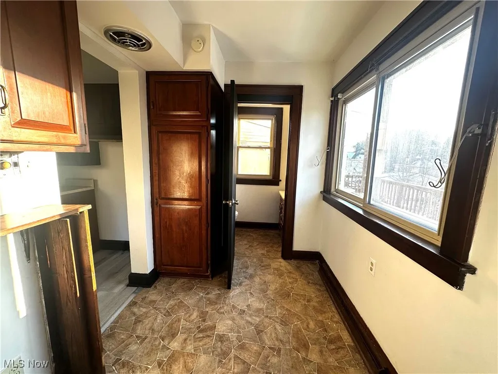 Corridor featuring stone finish flooring, visible vents, and baseboards