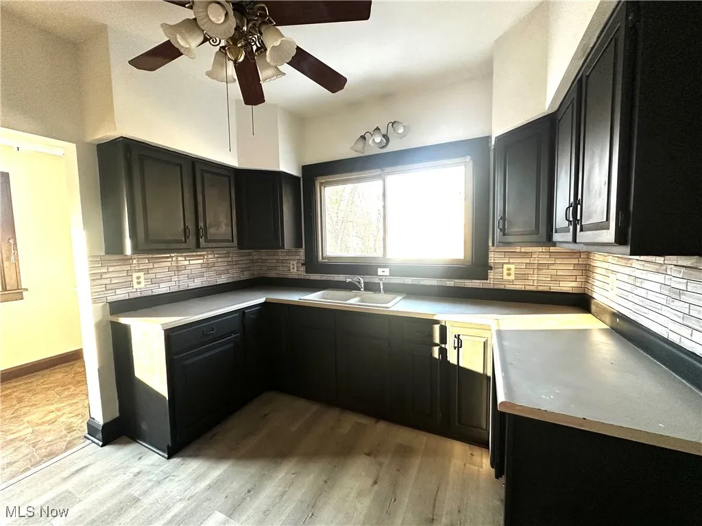 Kitchen featuring dark cabinets, backsplash, and a sink