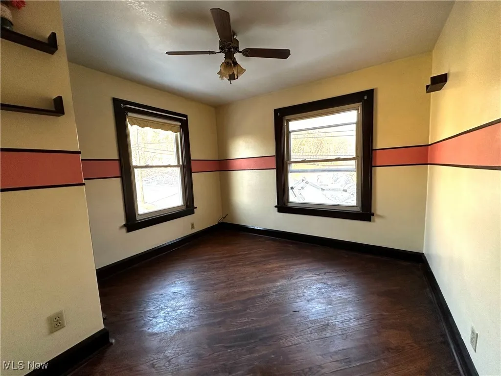 Unfurnished room with dark wood-style floors, a ceiling fan, and baseboards