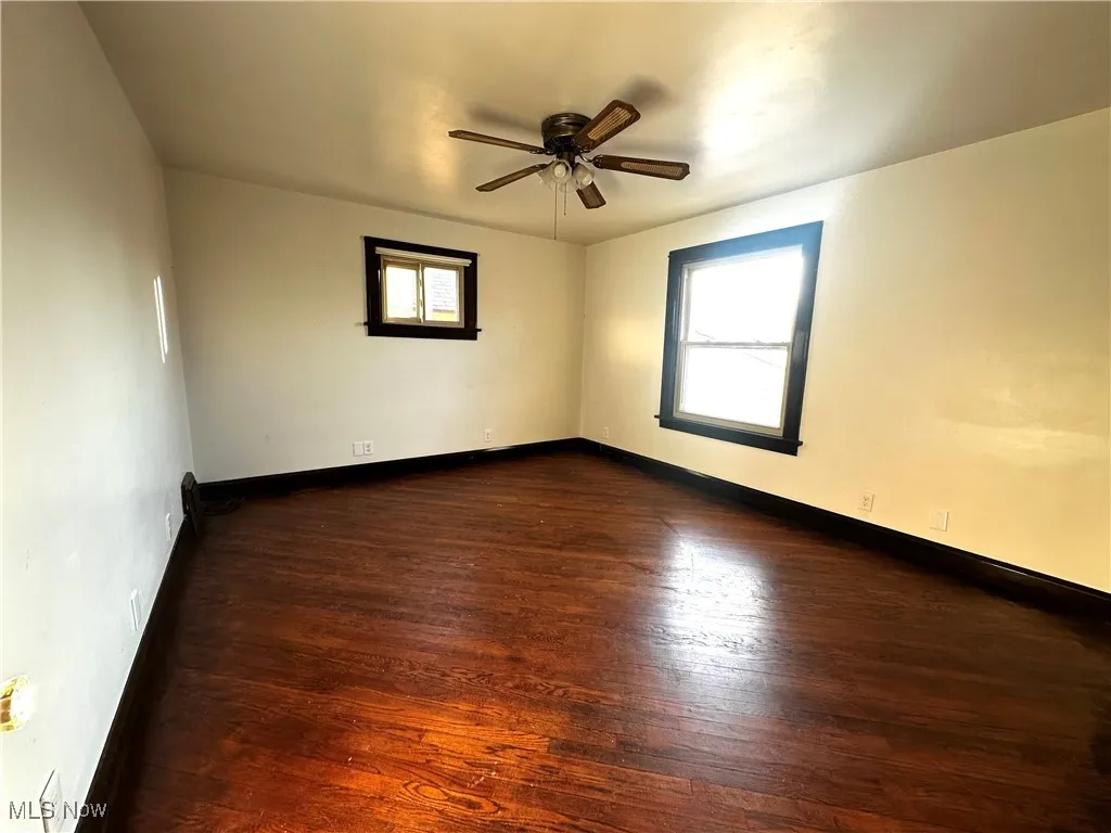 Spare room with dark wood-style floors, plenty of natural light, and baseboards