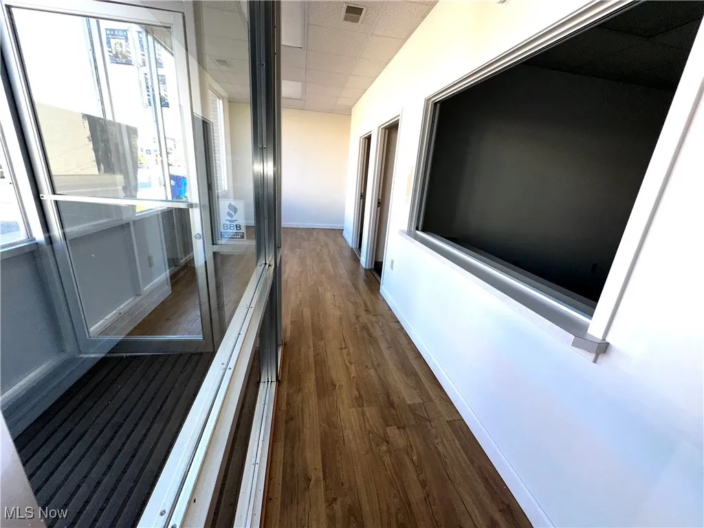 Hall featuring dark wood-type flooring, a drop ceiling, visible vents, and baseboards