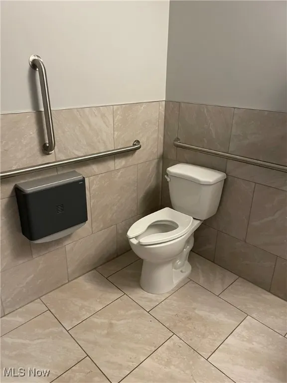 Bathroom featuring tile walls, a wainscoted wall, and tile patterned floors
