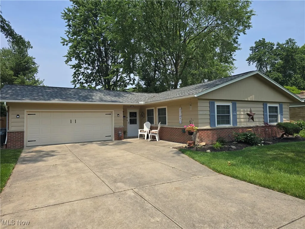 Ranch-style house featuring brick siding, a garage, driveway, and a front yard