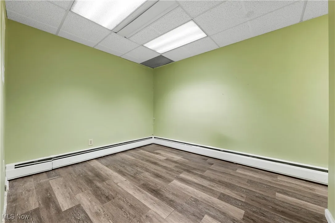 Spare room featuring a drop ceiling, wood finished floors, and a baseboard heating unit